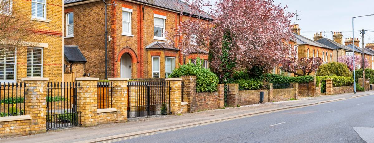 Brick houses behind low front walls, railings and gates on a residential street