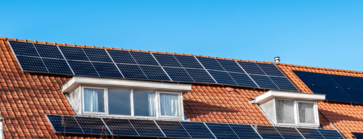 Solar panels on a red tiled roof with dormer windows